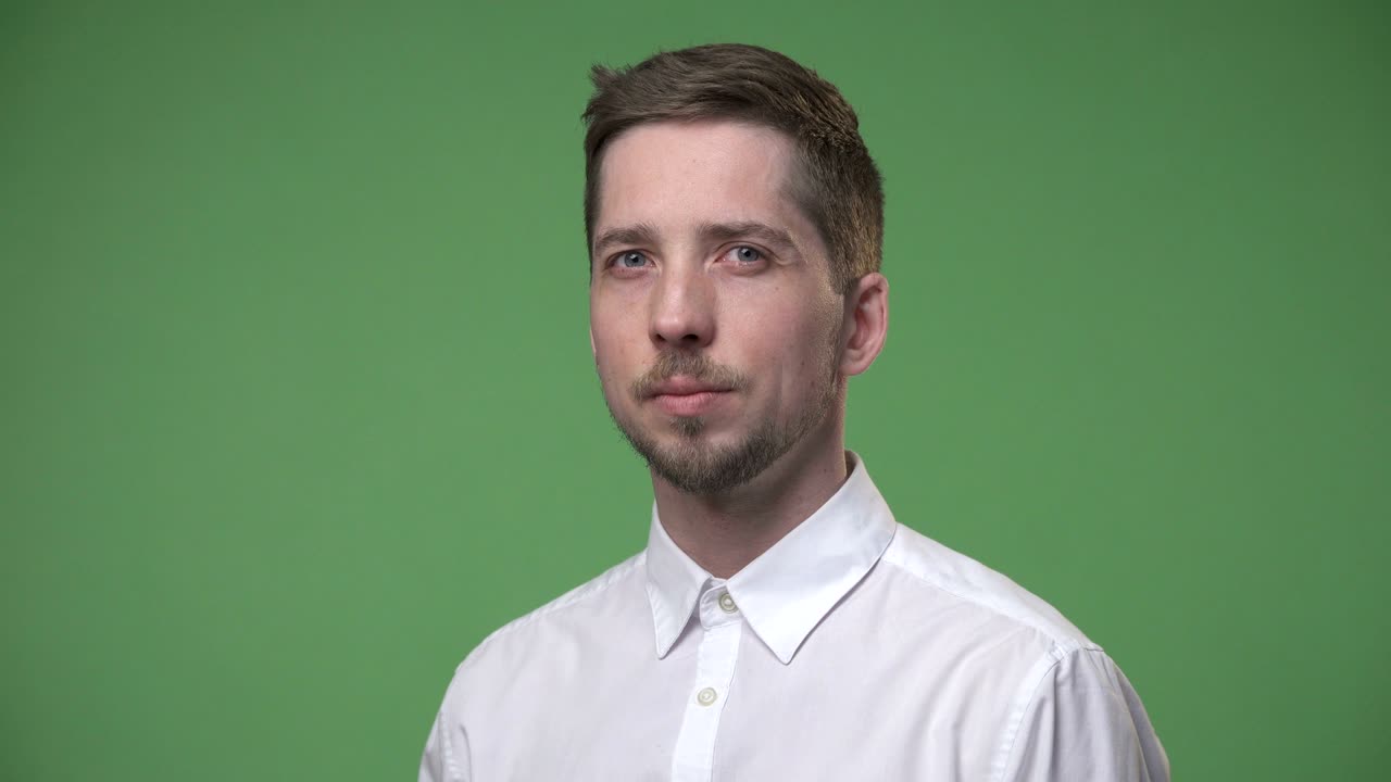 Serious young man in a white shirt, chroma key green screen background