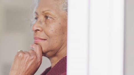 Glückliche-ältere-Afroamerikanische-Frau,-Die-Durch-Das-Fenster-Schaut