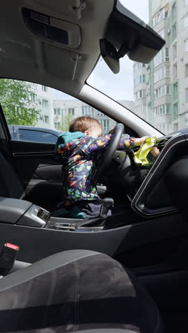 baby playing in the car with steering wheel. portrait of cute child having fun. vertical video.