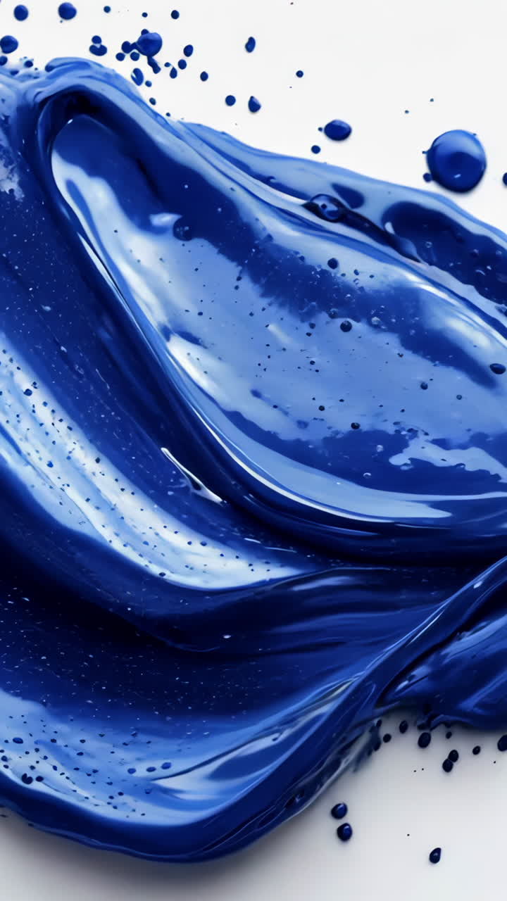 A blue paint splatter with a white background. The splatter is in the shape of a wave