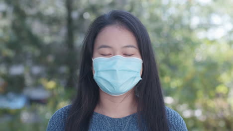 asian american young woman wearing a face mask outdoors, close up