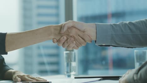 close-up of the businesswoman and businessman closing the deal and shaking hands in agreement. close-up on hands two businesspeople conclude a contract with a handshake.