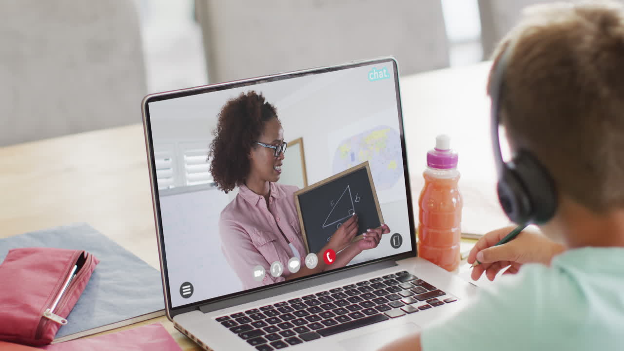 Caucasian boy using laptop for online lesson with african american female teacher on screen