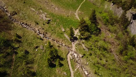 drone view of a hiking trail and a brook in the swiss alps