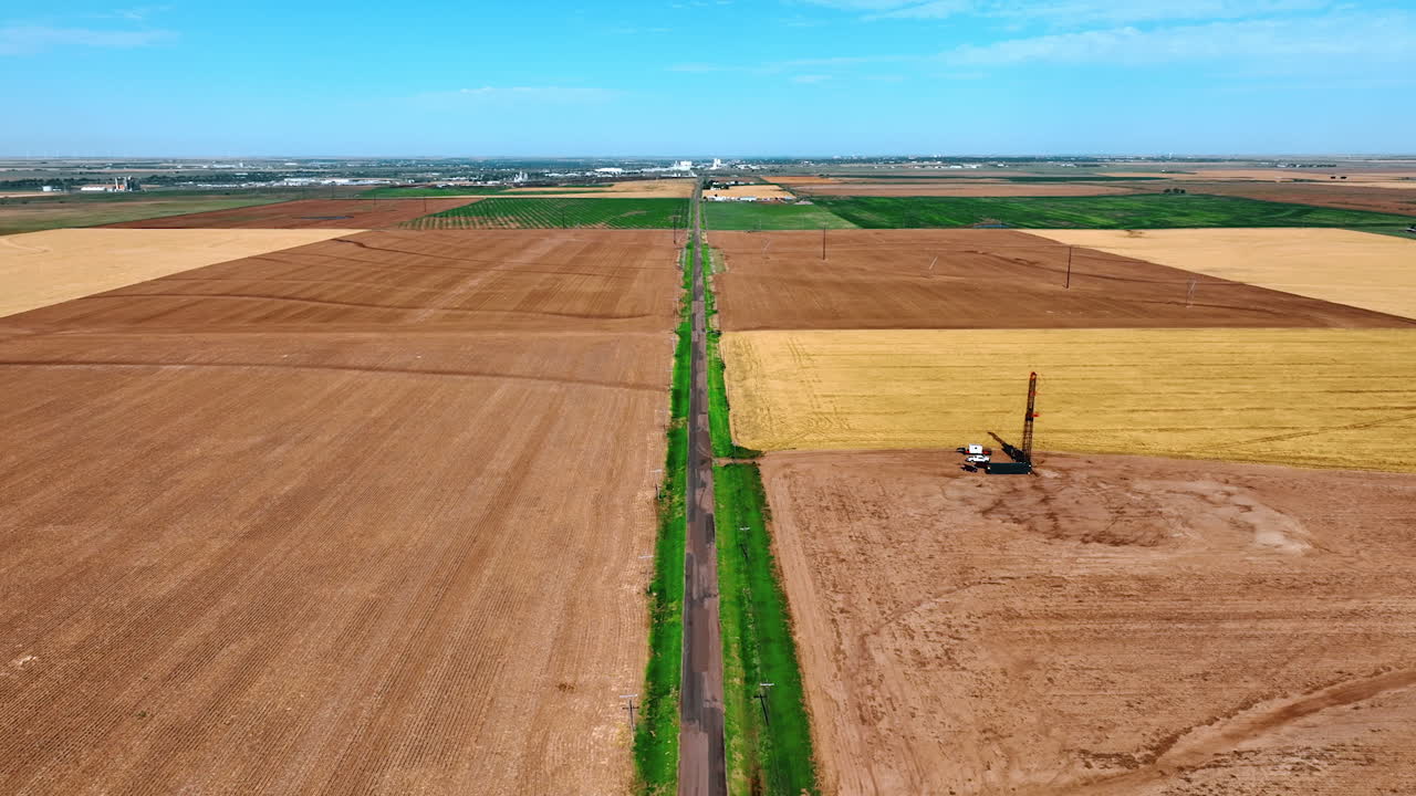 Flying above the road crossing the agricultural fields. Highway leading to the site for oil production.