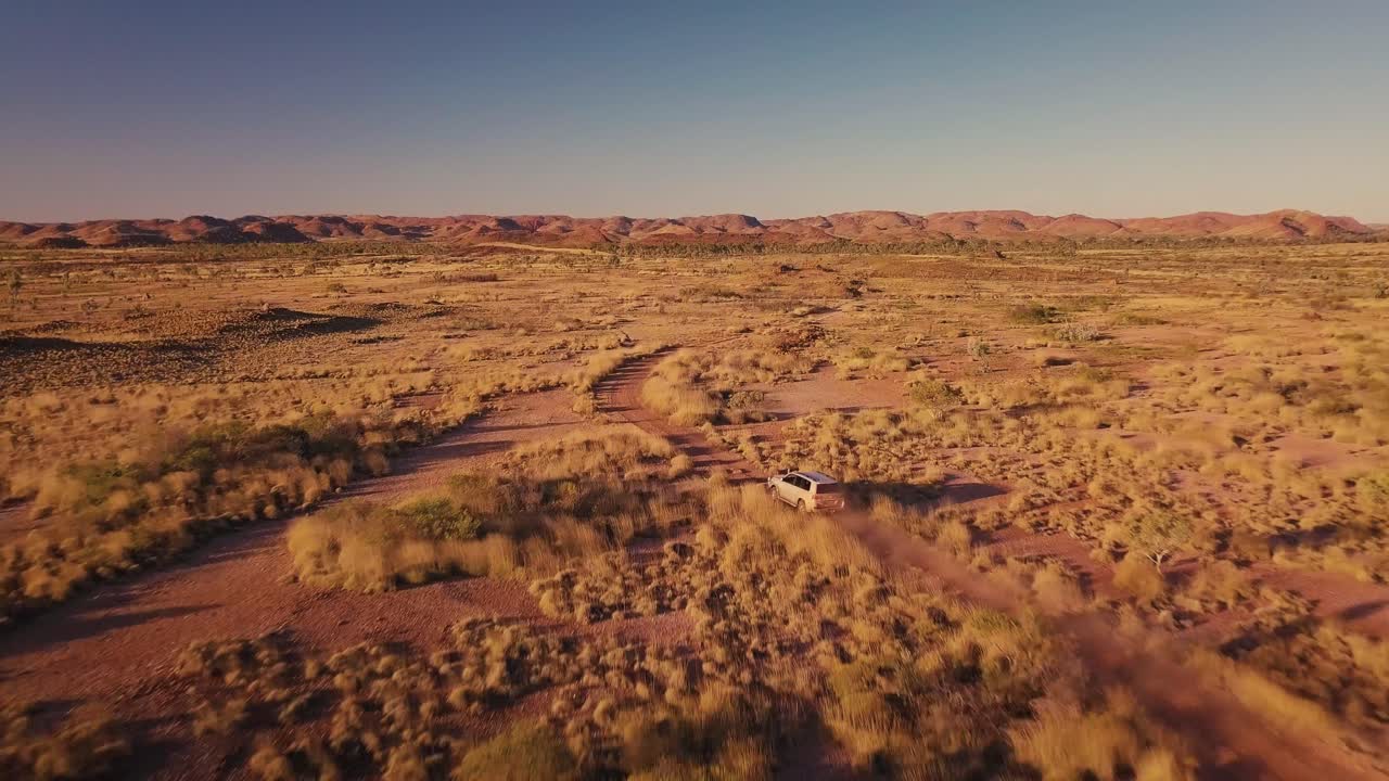 drone aéreo siguiendo un camión 4wd por un camino de grava en el desierto australiano