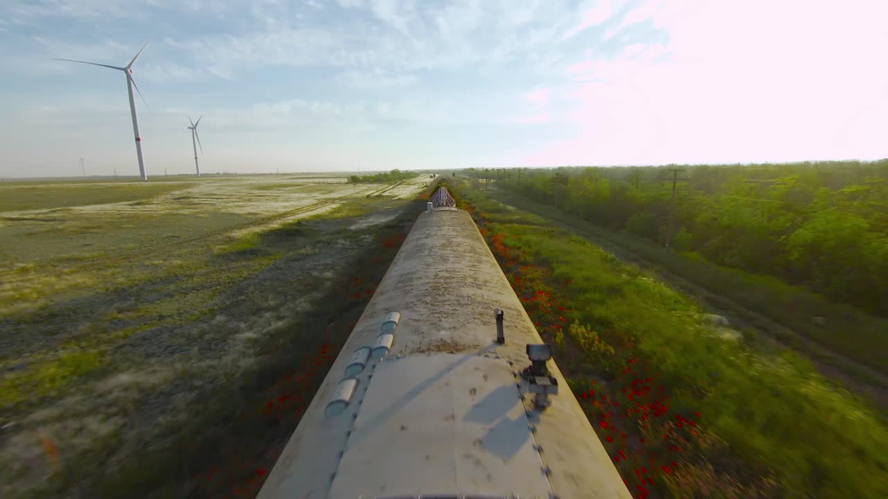 tren que pasa por un paisaje rural con turbinas eólicas