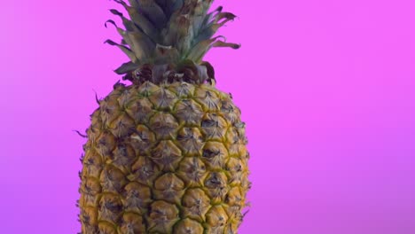 Ripe-whole-pineapple-on-a-vibrant-purple-background,-highlighting-its-texture-and-color