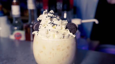 making a cocktail with wipped cream and oreos in slow motion with little chocolate marbles on top