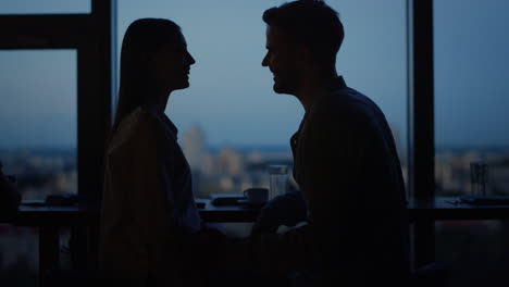 Young-couple-kissing-in-front-of-panoramic-windows.-Couple-hugging-in-office