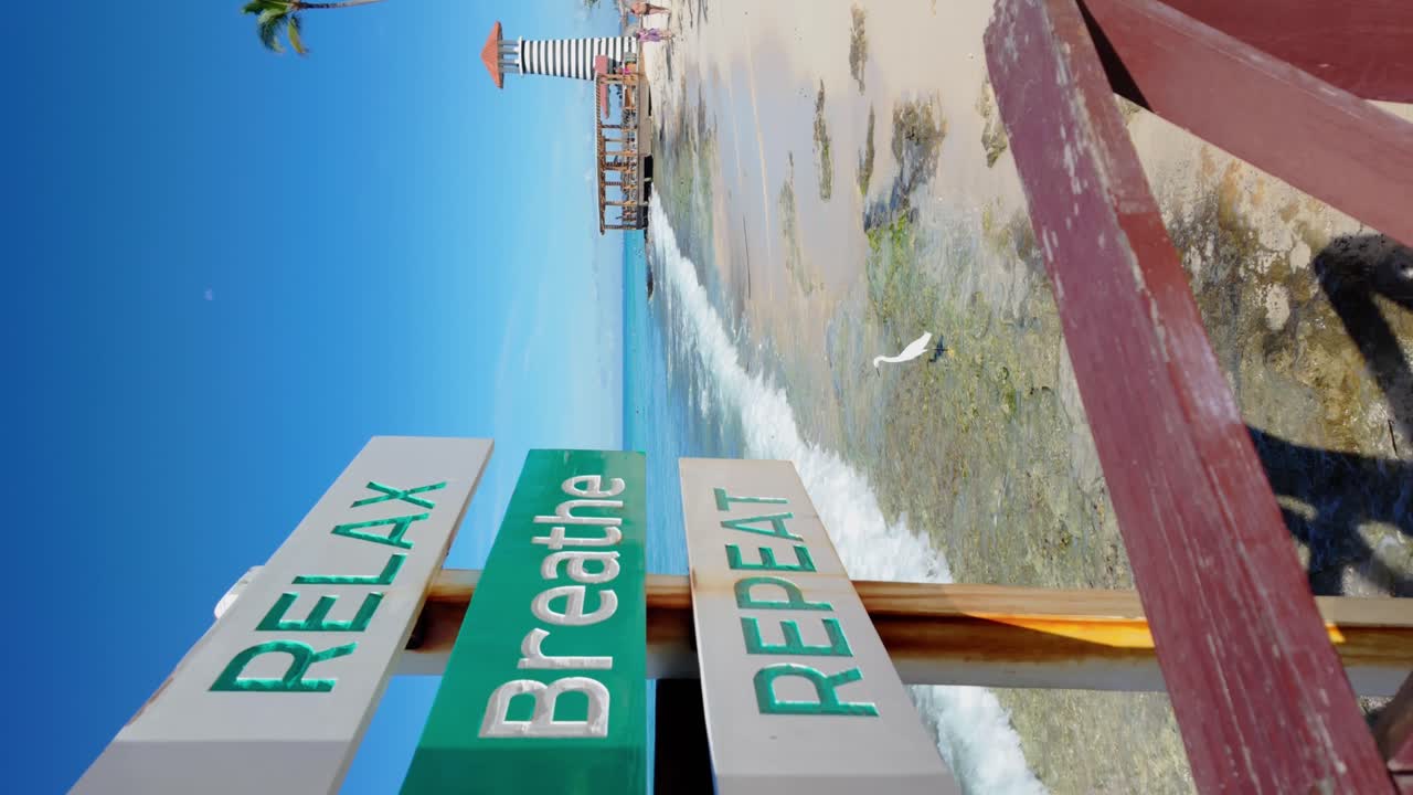 Sign with inscription relax, breathe, repeat. Pier and lighthouse of Playa Dominicus beach, Bayahibe in Dominican Republic. Slow-motion