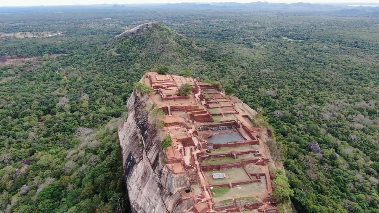 vista aérea de la fortaleza de roca de sigiriya en sri lanka rodeada de selva verde y montaña con roca de león en el fondo