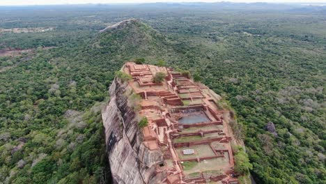 Vista-Aérea-De-La-Fortaleza-De-Roca-De-Sigiriya-En-Sri-Lanka-Rodeada-De-Selva-Verde-Y-Montaña-Con-Roca-De-León-Al-Fondo