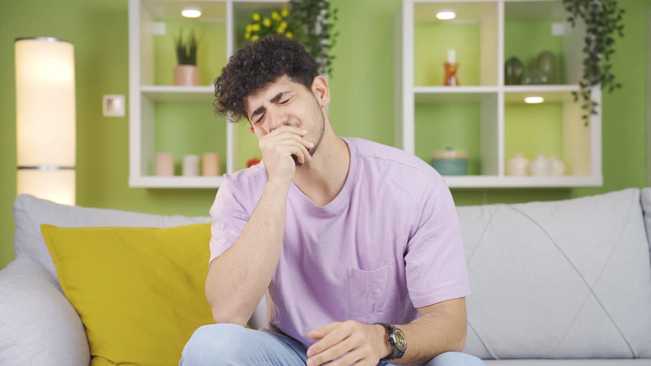 Sleepy young man at home yawning.
