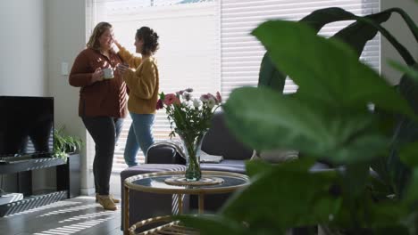 caucasian lesbian couple embracing and drinking coffee