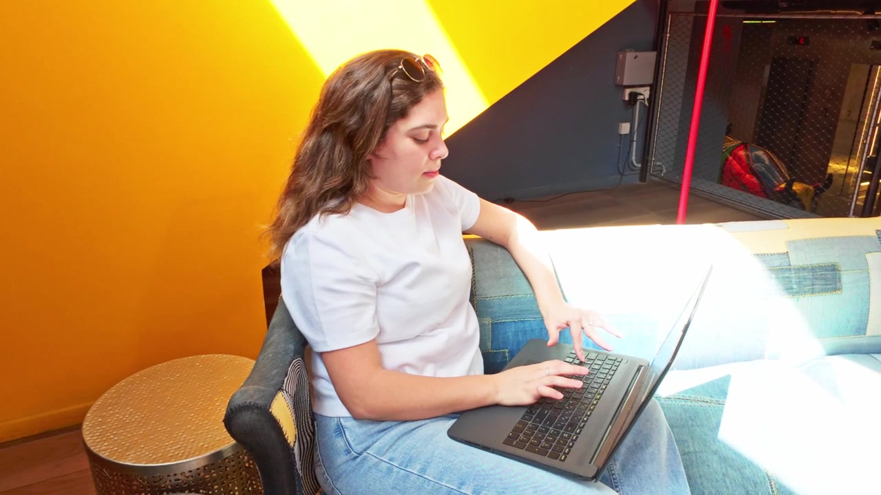 Donna che lavora da remoto al laptop in una lobby moderna