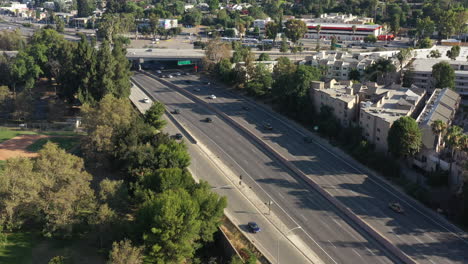 Aerial-drone-shot-over-the-101-freeway-in-California,-USA-with-traffic-moving-up-and-down-during-eveningtime