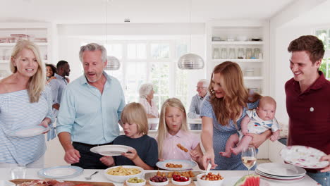 multi-generation family and friends gathering in kitchen for celebration party