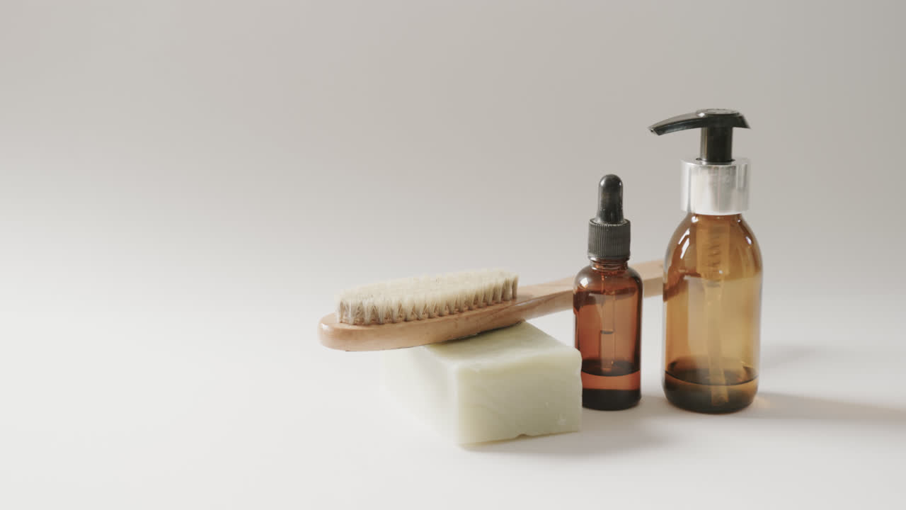 Close up of glass bottles with pumps, soap, brush and copy space on white background