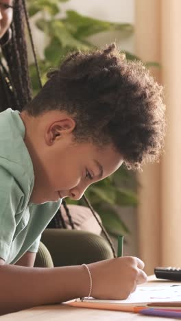 child focused on drawing with a parent nearby