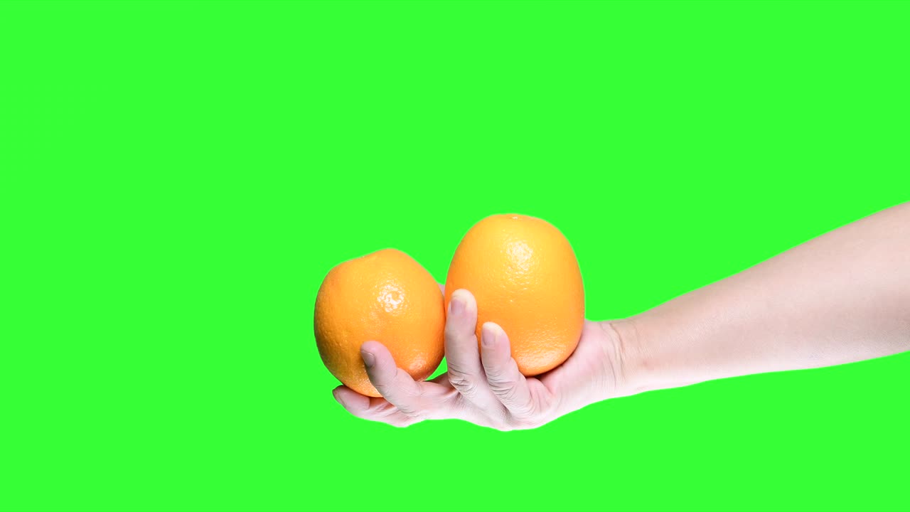 Mano che tiene un'arancia isolata su sfondo green screen.