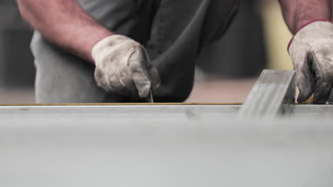 metal frame fabrication - metalworker marking measurements on a tubular with tape measure for accuracy - static shot
