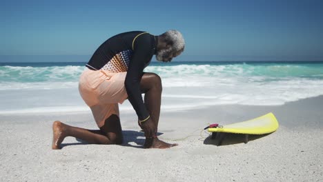 hombre mayor preparándose para surfear en la playa