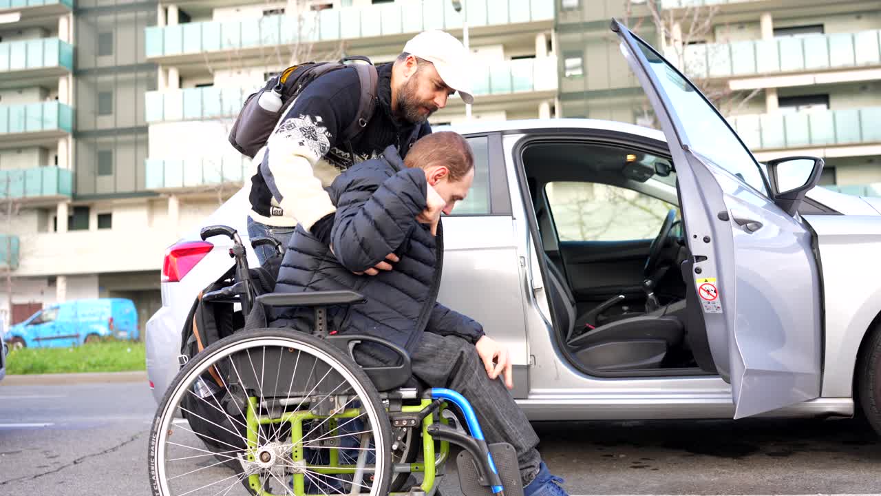 Man being assisted into car from wheelchair