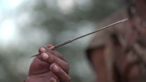 an ethic hand holding a sharp handmade dart coming into focus