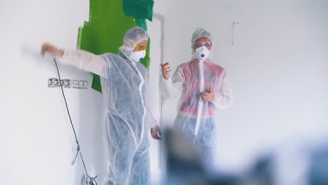 couple in protective suits and respirators in light room