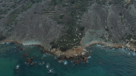 Hermosa-Costa-De-La-Isla-Mediterránea-Con-Olas-Azules-Del-Océano-Rompiendo-En-Las-Rocas,-Vista-Aérea-Inclinada-Hacia-Abajo