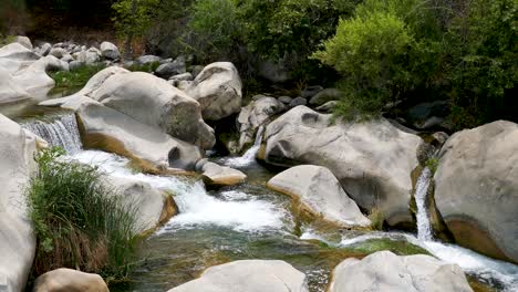 un río de montaña con agua dulce que fluye a través de un estrecho lecho rocoso y forma un pequeño estanque