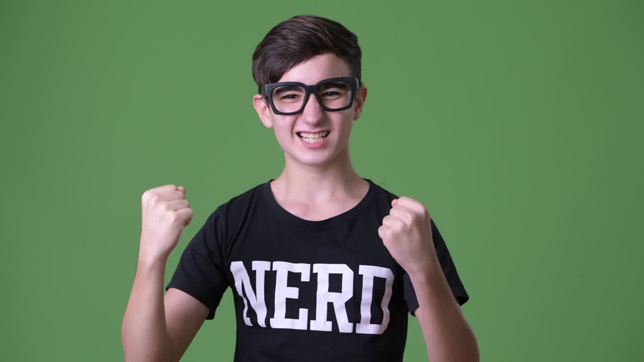 Young handsome Iranian teenage boy against green background