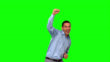 un hombre de negocios alegre levantando el puño en la pantalla verde.