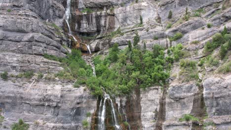 backward aerial of bridal veil falls from steep brown majestic mountains in utah, provo canyon