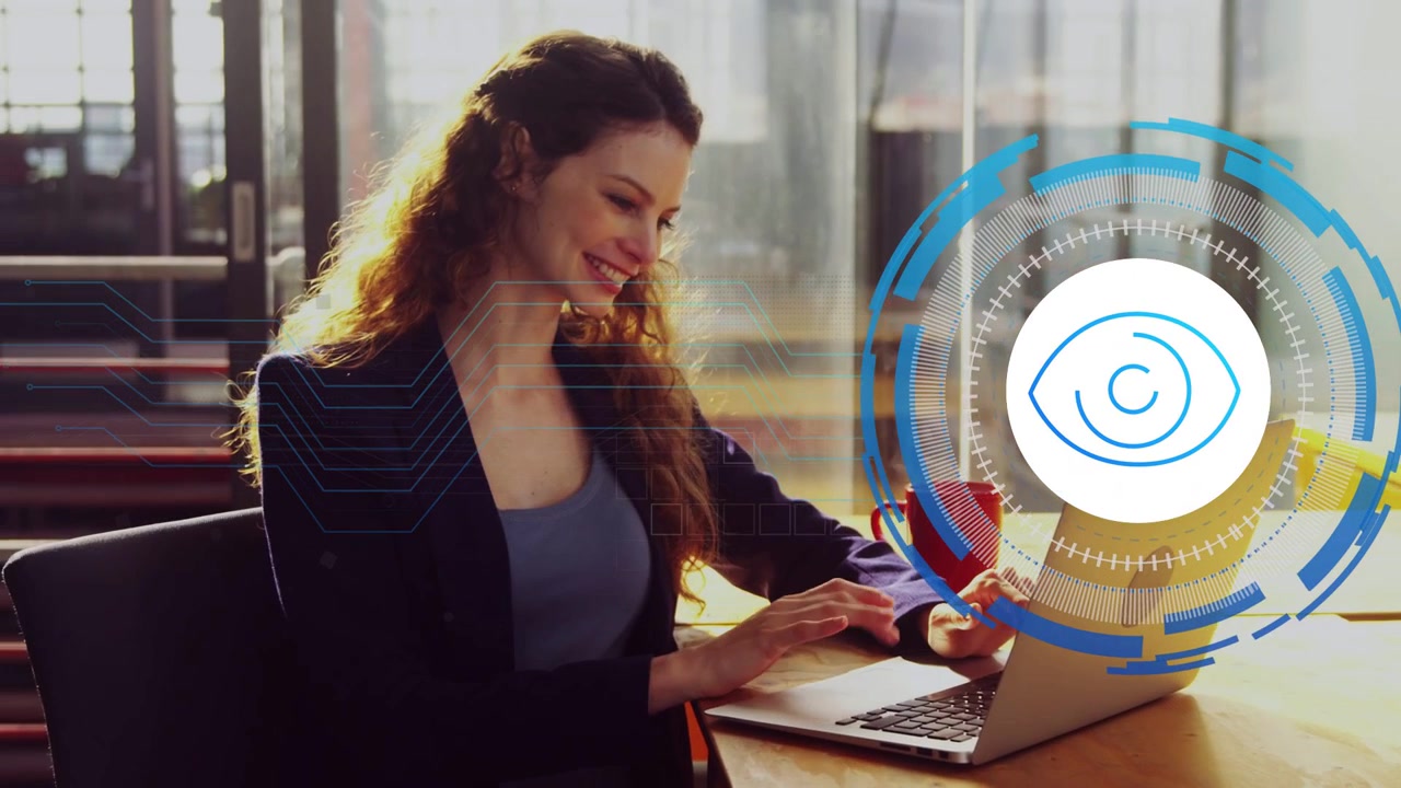 Donna di mezza età in ufficio che digita al laptop, appare un'icona a forma di occhio HUD, facendola sorridere e sorseggiare dalla tazza