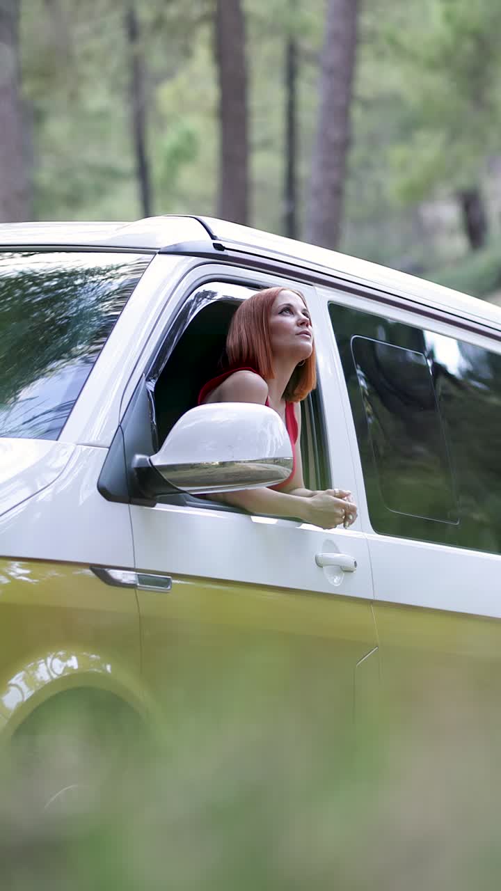 Giovane donna che guarda fuori dal finestrino dell'auto nella foresta