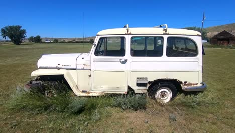 old abandoned vintage white jeep sitting in a field for years in alberta canada on a sunny day