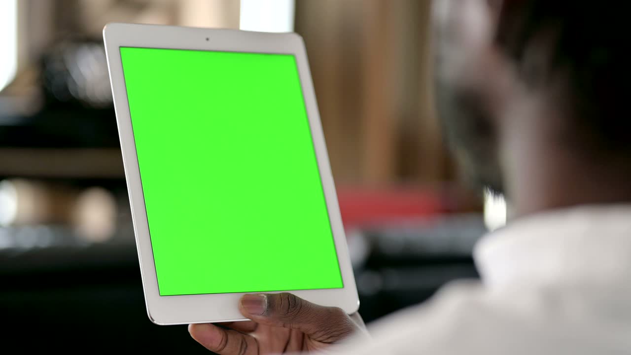 vista trasera de un hombre africano usando una tableta con pantalla de tecla cromada
