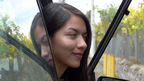 Beautiful-young-Hispanic-woman-smiles-and-looks-at-camera,-sitting-in-a-car