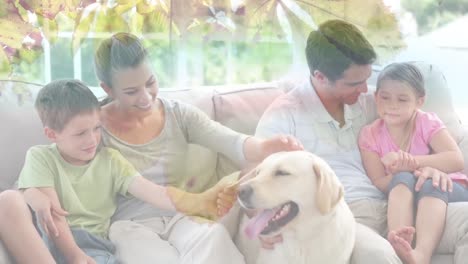 composite video of leaves on the branch against caucasian family playing with their dog at home