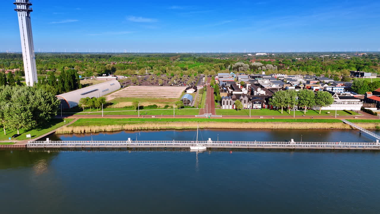 Footage along the beautiful picturesque waterfront of Lelystad, The Netherlands. View on the lovely houses, storehouses and telecom tower.