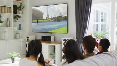 Composite-of-happy-family-sitting-at-home-together-watching-athletics-javelin-event-on-tv