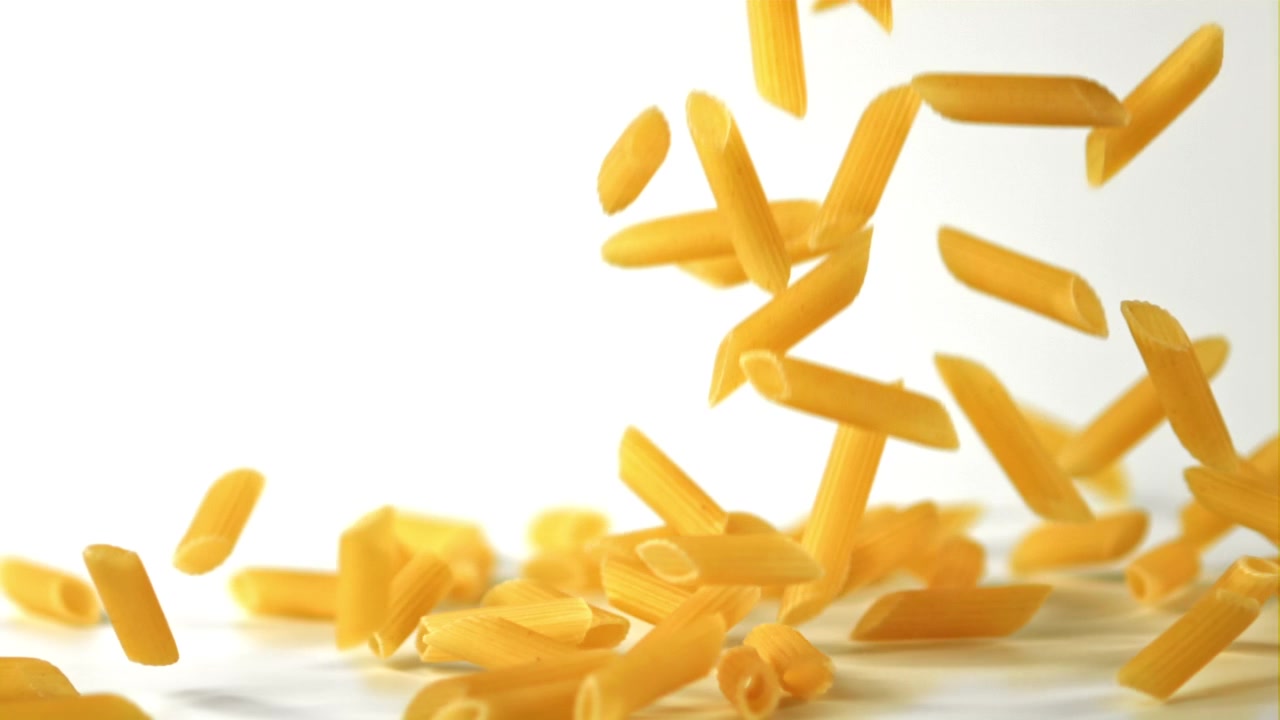 Penne che Cadono al Rallentatore su Sfondo Bianco