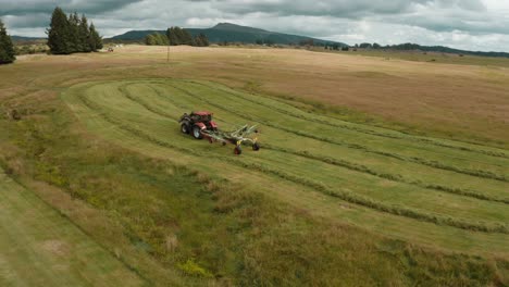 trattore che utilizza una macchina rastrellatrice per fieno montata in preparazione per l'imballaggio, voltafieno