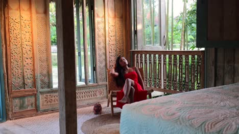 young asian sitting in bohemian bedroom villa with natural garden views outside in bali