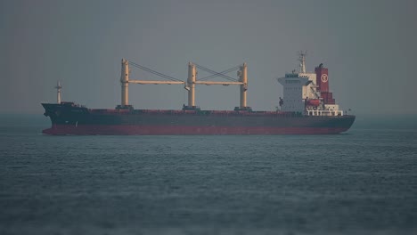 A-huge-cargo-ship-in-the-open-water-near-the-port-of-Hirtshals-Timelapse,-tilt-shift-video