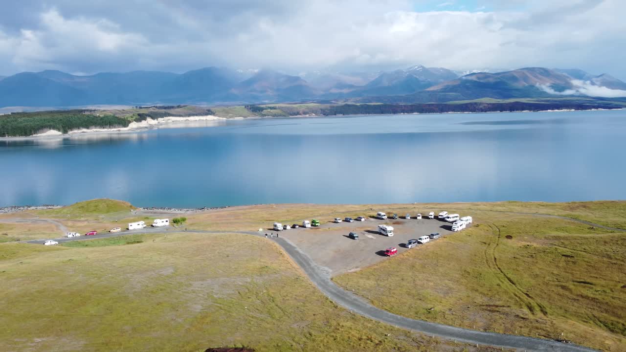 Drone view of caravans and campervans on a freedom camping spot on a sunny summer day next to Lake Pukaki and mountains in New Zealand.