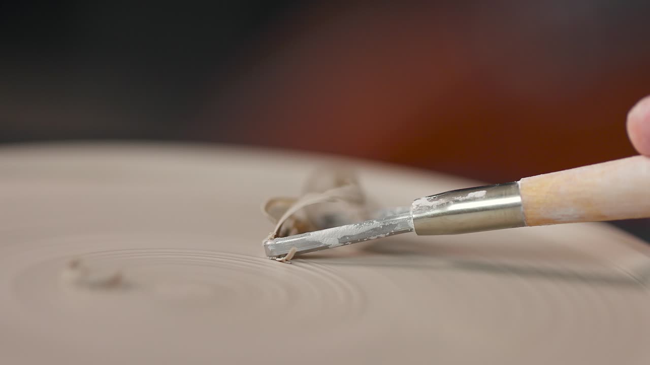 도자기 스튜디오에서 도구로 작업 조각을 형성하는 여성의 손의 클로즈업. 점토 어리. 느린 모션