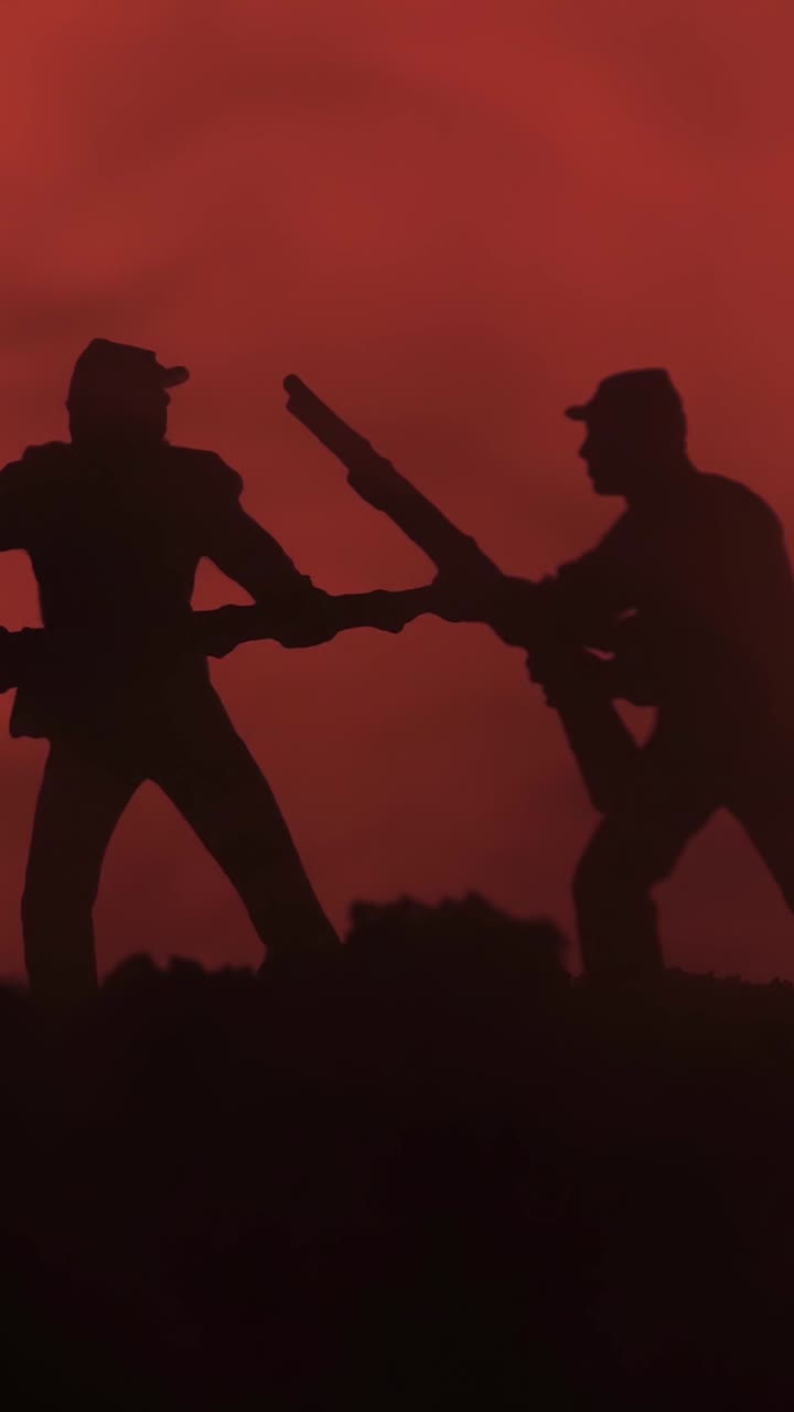 Toy soldiers fighting with rifles against smoky orange battlefield backdrop in pan shot